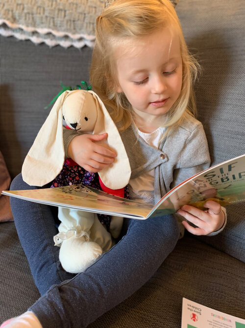 Little blond girl reading a book with her pet